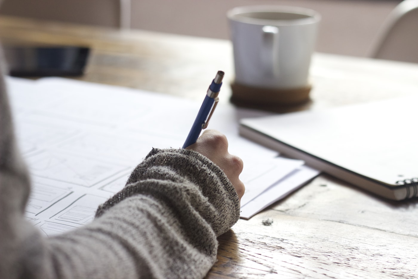 A hand planning on paper at a desk